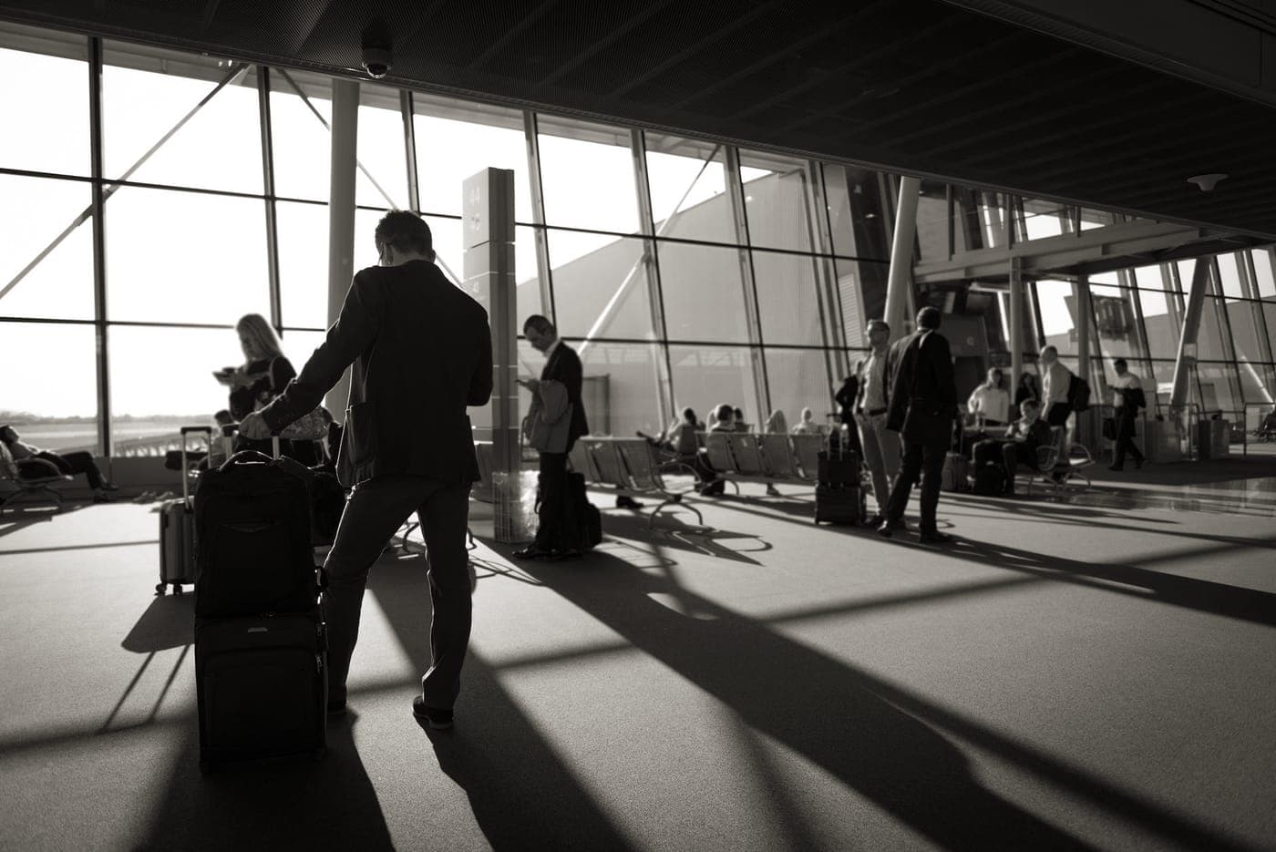 A traveler walking through an airport terminal pulling a cabin suitcase