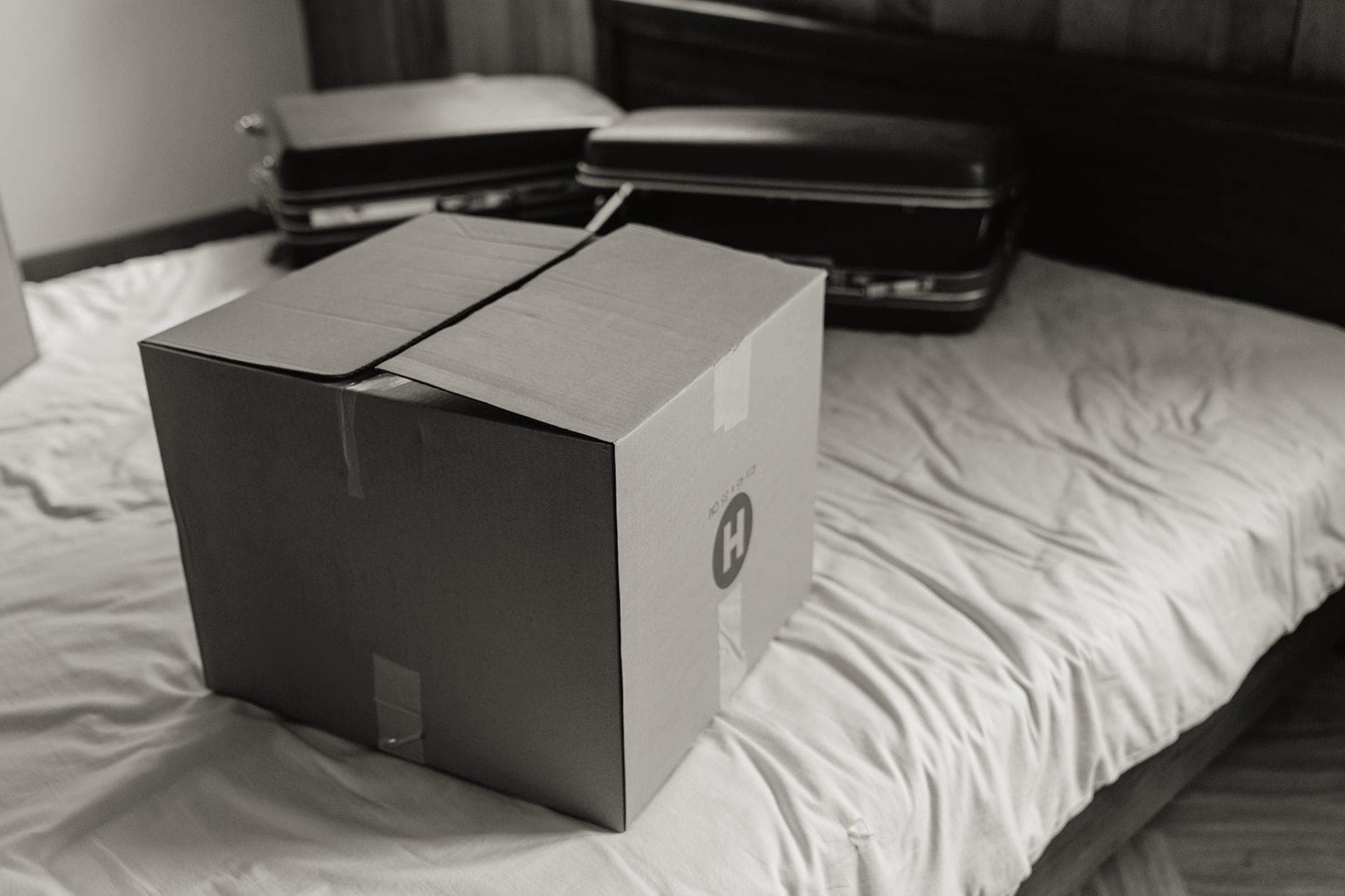 An open suitcase part-packed on a bed with folded clothes beside it